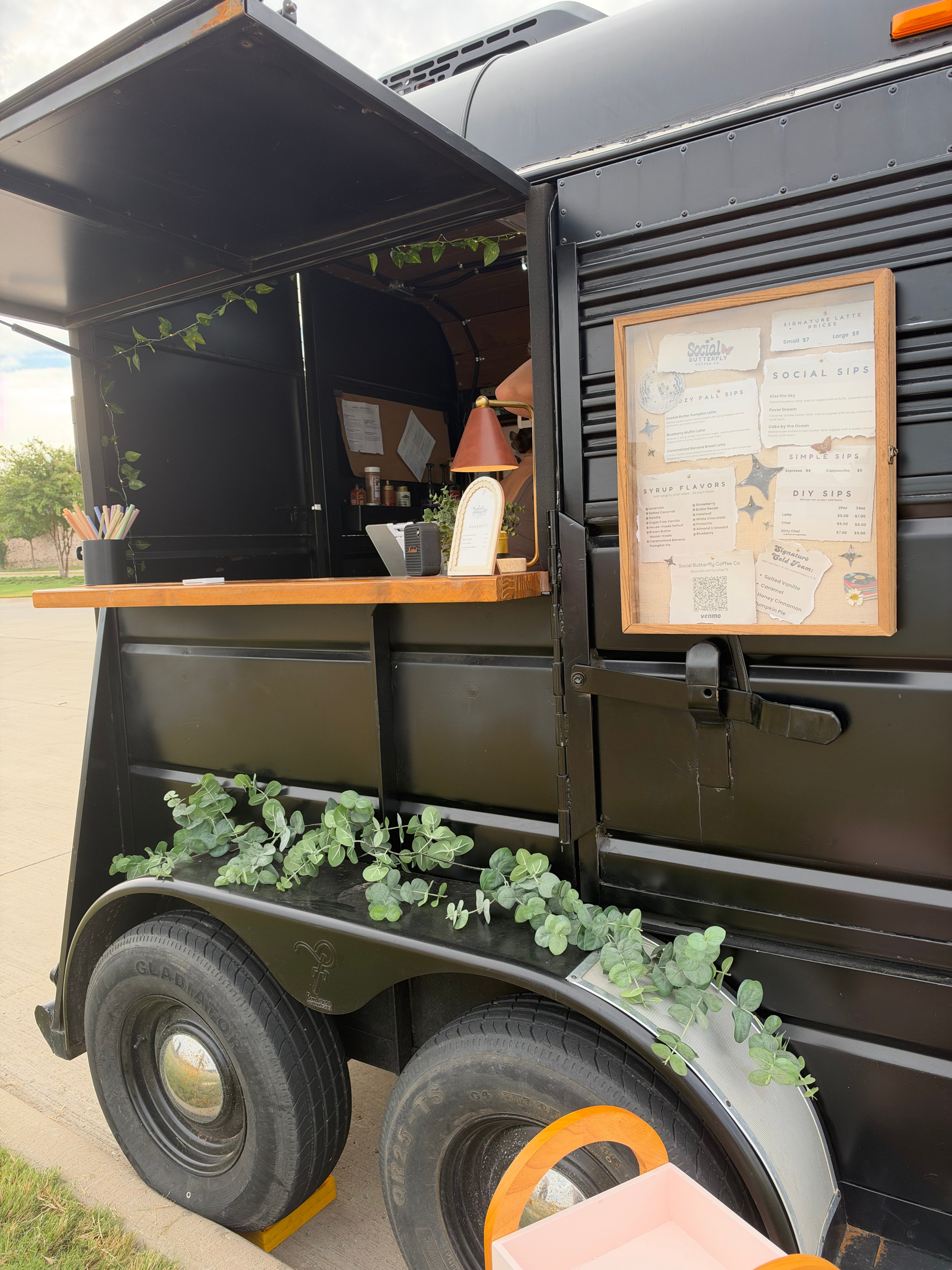 Side view of the Social Butterfly Coffee Co trailer with menu board and eucalyptus